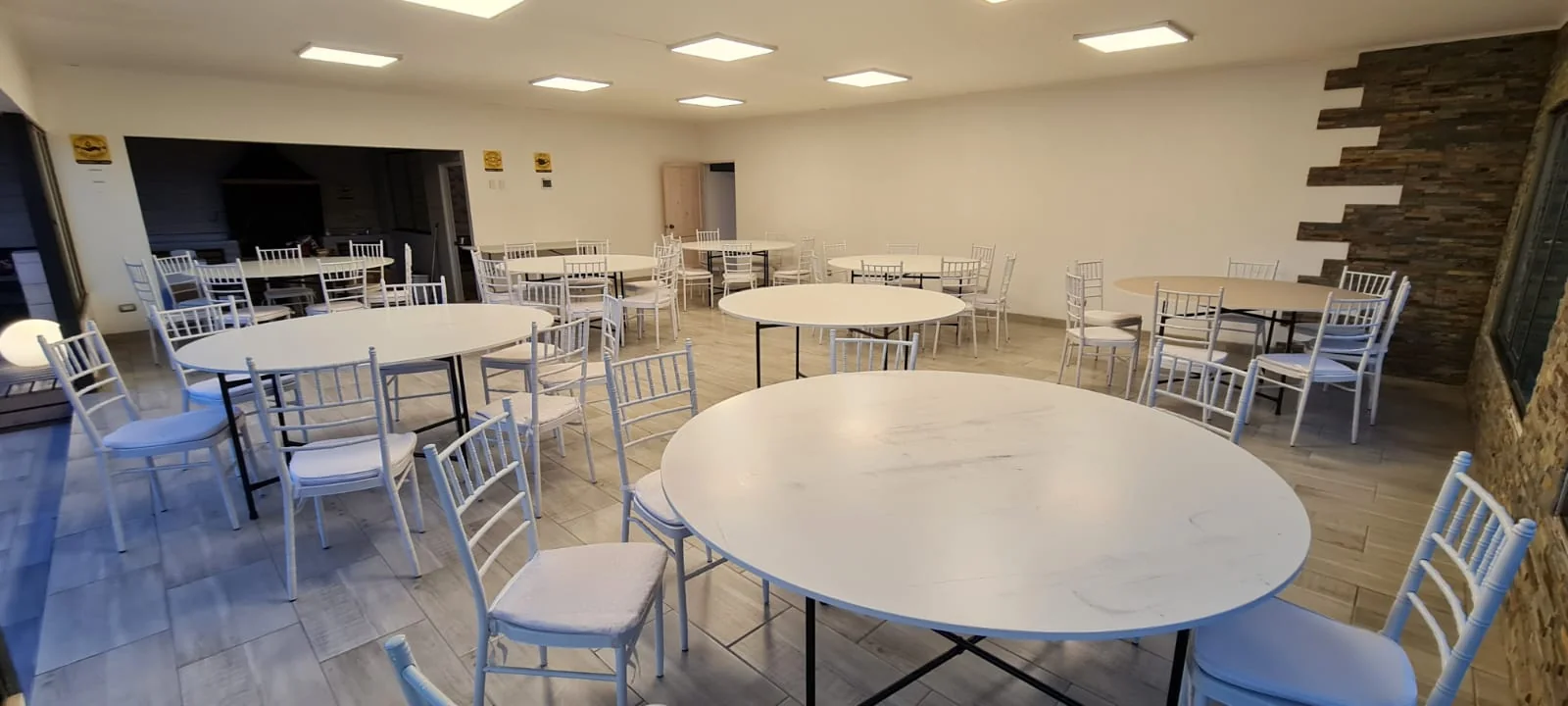 Salón interior con mesas redondas y sillas Chiavari